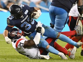 Toronto Argonauts running back Andrew Harris (33) is tackled by Montreal Alouettes linebacker Chris Ackie (21) during first second CFL football action in Toronto Thursday, June 16, 2022.