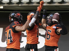 BC Lions' Bryan Burnham, right, celebrates with teammates Keon Hatcher, left, and Dominique Rhymes after scoring a touchdown against the Toronto Argonauts during CFL action in Vancouver on June 25.
