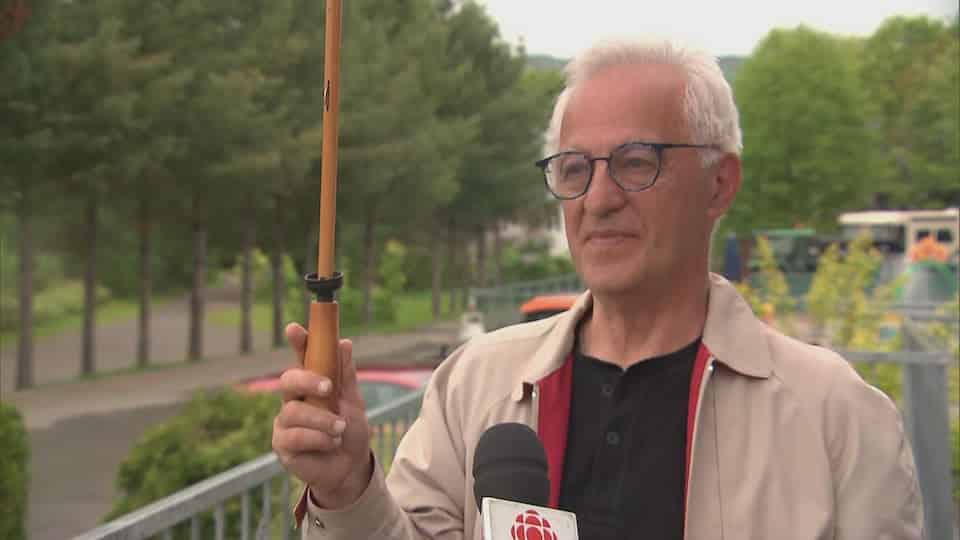 The director general of the Cité Joie camp Denis Savard is interviewed by Radio-Canada in Quebec.  He is holding an umbrella.