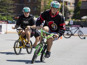 Ottawa Senators defenseman Nick Holden races Ottawa Police Superintendent Ken Bryden on kid sized bikes after giving kids from Bayshore Public School bike helmets.