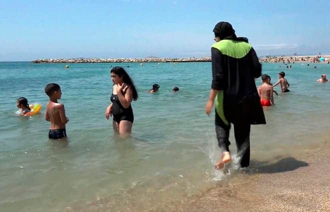 In this August 4, 2016, file photo made from video, Nissrine Samali, 20, dives into the sea wearing a burkini, a wetsuit-like garment that also covers her head, in Marseille. , In the south of france.  France's top administrative body ruled Tuesday against allowing body coverings. "burkini" bathing suits in public swimming pools for religious reasons.