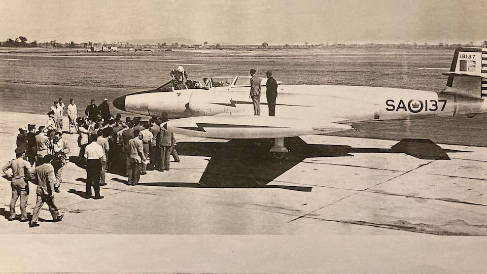Newspaper clipping showing a photo of a bomber plane greeted by large numbers of people on the airport tarmac. 