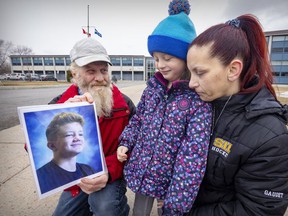 Lynne Baudouy and Guy Gaudet with daughter Angele outside St. Thomas High School in Pointe-Claire, in April.  Their son Lucas died after being stabbed during an altercation near the school in February.