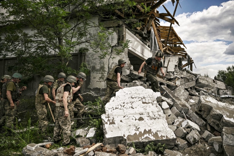 Ukrainian soldiers inspect a destroyed warehouse