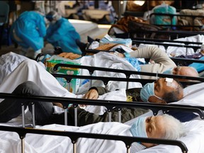 Patients wearing face masks rest at a makeshift treatment area outside a hospital, following the COVID-19 outbreak in Hong Kong, China, March 2, 2022.