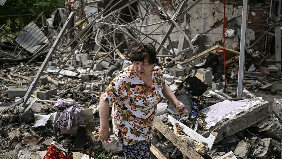 A woman among the rubble of a house. 