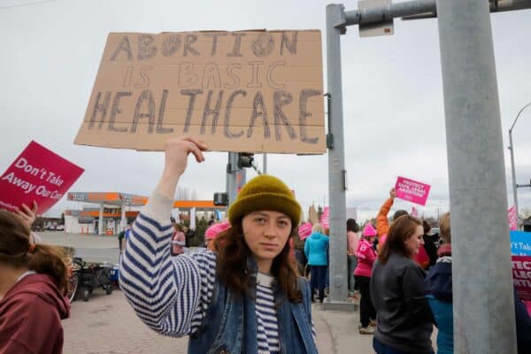 a person holds a sign that says "Abortion is basic medical care."