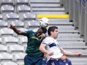 York United's Chrisnovic N'sa, left, and Vancouver Whitecaps' Brian White vie for the ball during the first half of a Canadian Championship semifinal soccer match, in Vancouver, on Wednesday, June 22, 2022.
